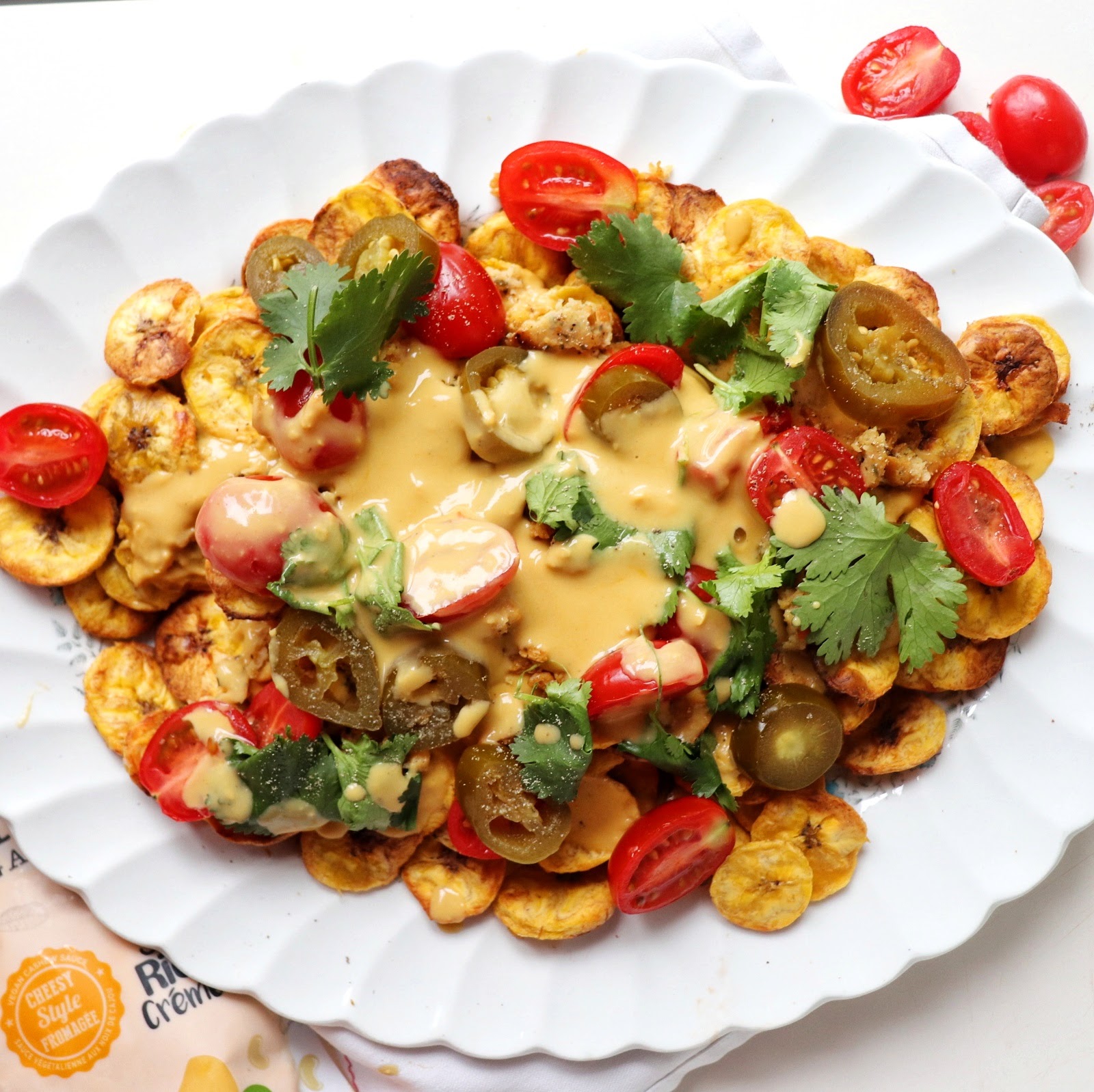A plate of nachos loaded with cheesy sauce and healthy toppings, garnished with cilantro.