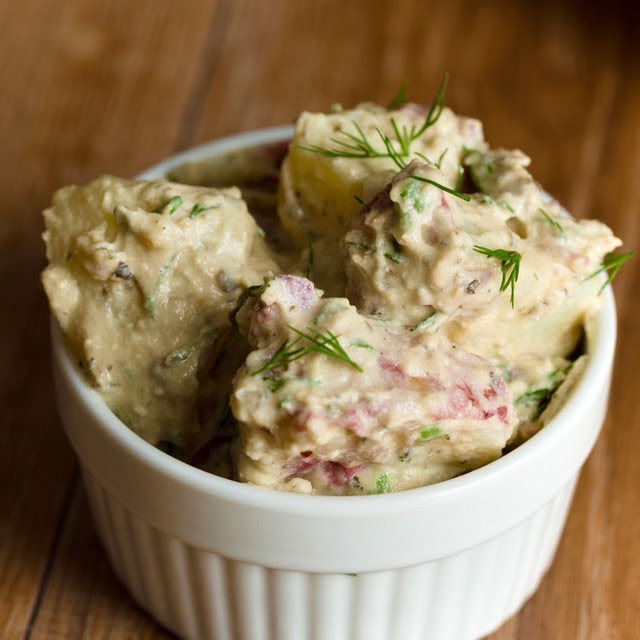 A white ramekin contains chunky redskin potatoes, slathered in dilly Alfredo sauce.