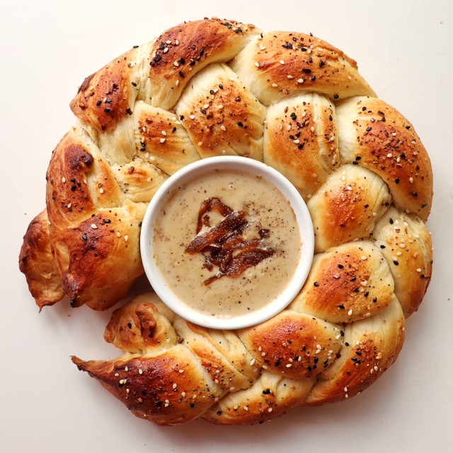 A circle of braided fluffy bread encircles a white ramekin filled with warm and creamy NONA Carbonara.