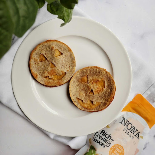 NONA Cheesy sauce shines through the smiles of two Jack o Lantern quesadillas, grinning up from their place on a white dinner plate.